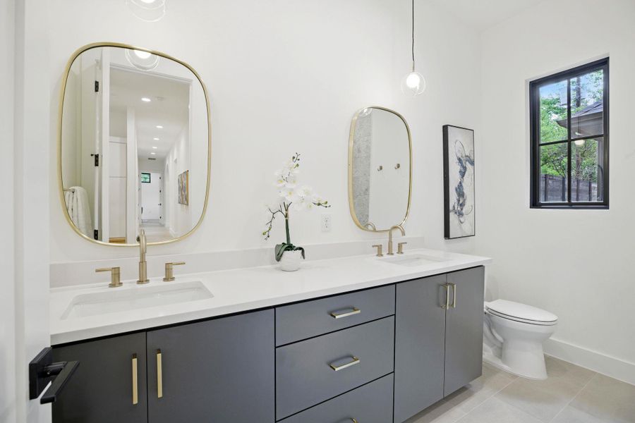 Bathroom featuring double vanity, toilet, tile patterned flooring, and baseboards