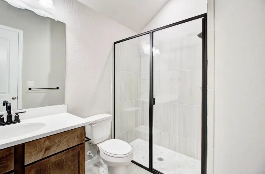 Bathroom with a textured wall, vanity, a shower stall, and lofted ceiling Bathroom with a textured wall, vanity, a shower stall, and lofted ceiling