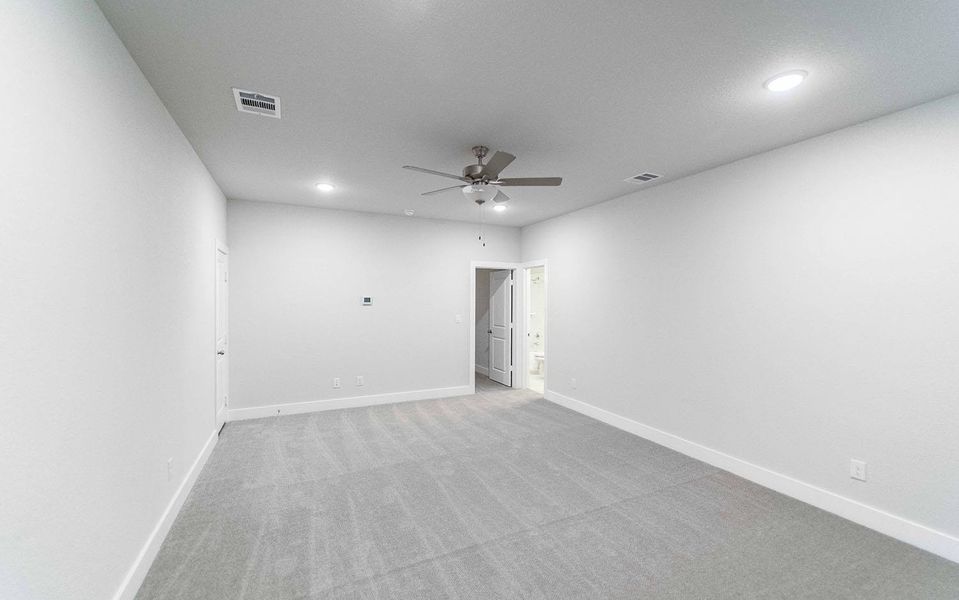 Empty room featuring light carpet, baseboards, visible vents, and ceiling fan