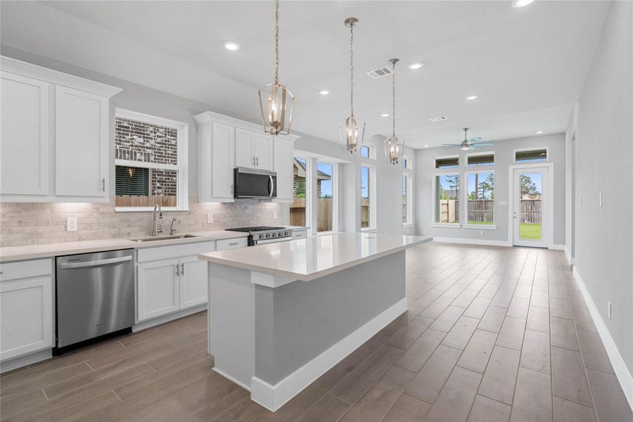 As you step past the front of the home, you are immediately welcomed by a bright, open-concept kitchen that serves as the home's focal point. The space feels clean and modern, anchored by a large quartz-topped island that seamlessly connects the cooking area to a long, light-filled living space.