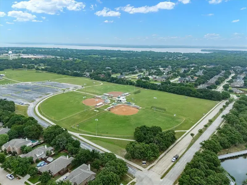 Aerial perspective showcasing expansive green spaces, multiple baseball diamonds, and a large parking area