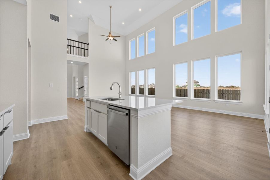 Kitchen with open floor plan, white cabinetry, dishwasher, a kitchen island with sink, and light wood finished floors