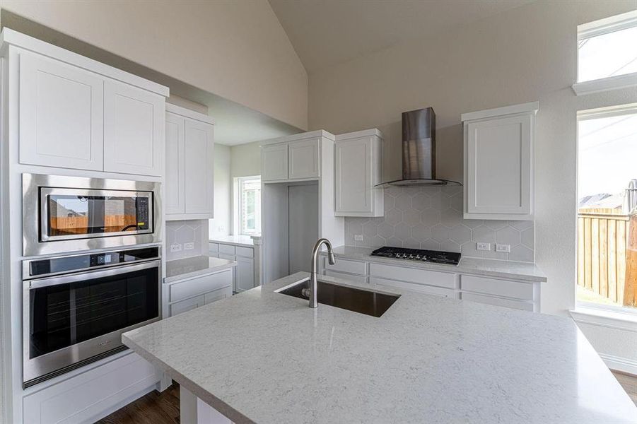 Kitchen featuring sink, decorative backsplash, stainless steel appliances, and wall chimney exhaust hood