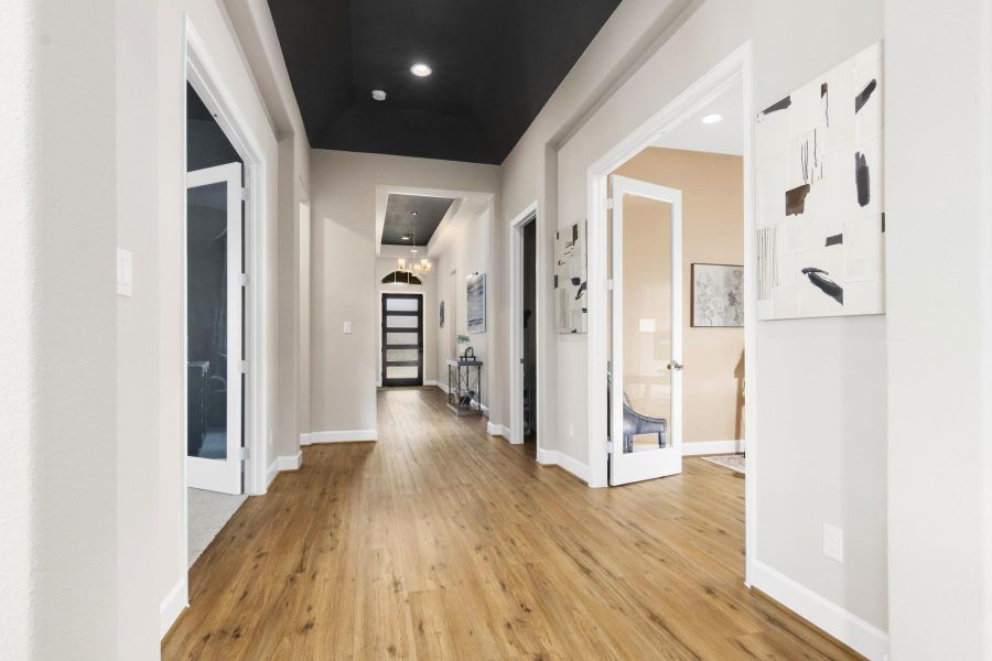 This photo showcases a bright, spacious hallway with light wood flooring and a modern, open feel. The hallway leads to multiple rooms with glass doors, offering a clean and elegant design.