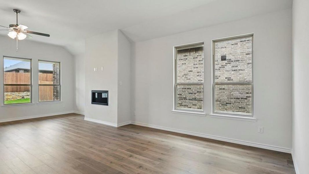 Spacious interior room featuring wood-finish flooring, white baseboards, and a built-in media niche