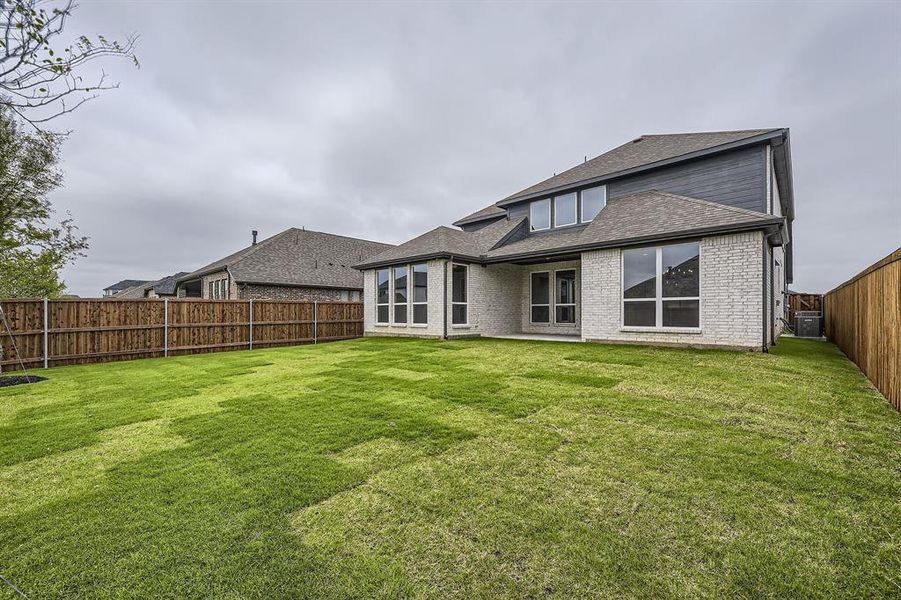 Back of house featuring central AC unit, roof with shingles, and brick siding