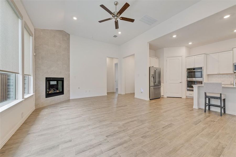 Unfurnished living room with ceiling fan, recessed lighting, a tile fireplace, and light wood-style floors Unfurnished living room with ceiling fan, recessed lighting, a tile fireplace, and light wood-style floors
