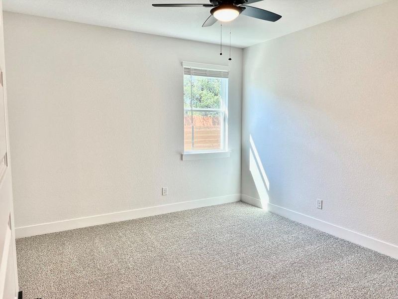 Carpeted empty room with baseboards and a ceiling fan