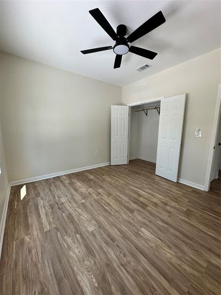 Unfurnished bedroom featuring dark wood-style floors, a closet, and a ceiling fan