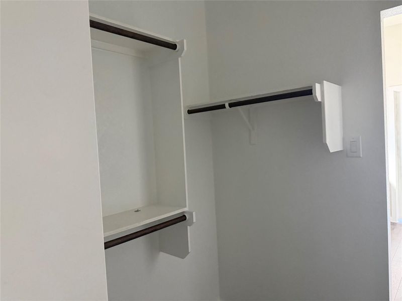 Custom built-in hanging rods optimize storage space in this functional walk-in closet.