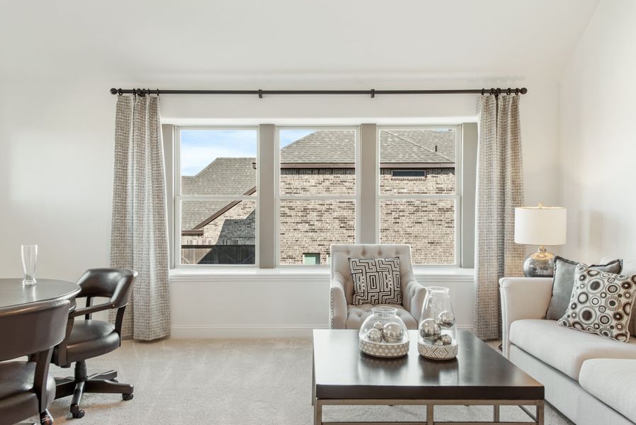 Living room with large bay window, neutral sofa, accent chair, and dark wood coffee table