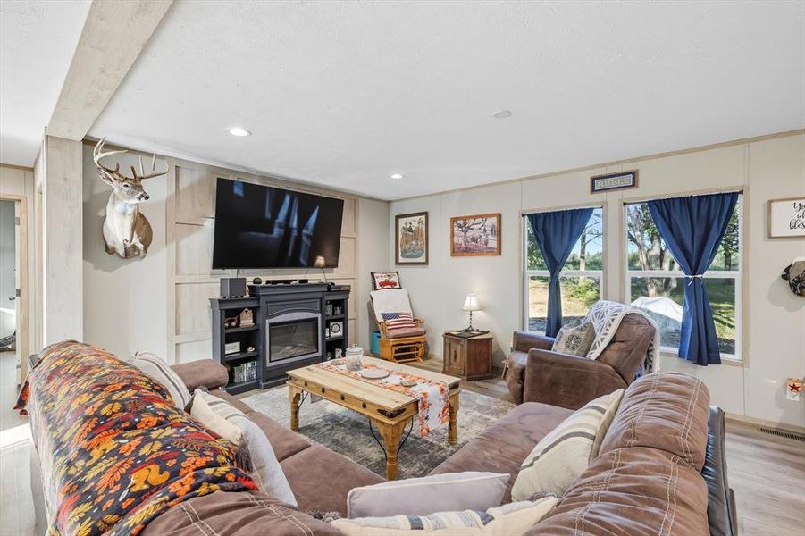 Living room with wood finished floors, recessed lighting, and a glass covered fireplace Living room with wood finished floors, recessed lighting, and a glass covered fireplace