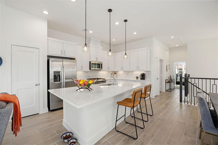The kitchen features a large asymetrical quartz island and pendant lighting