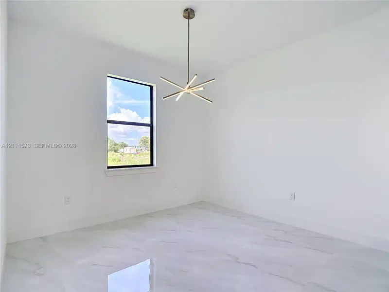 Modern room featuring stone-finish tile flooring, a multi-arm linear chandelier, and a single-hung window with a black frame