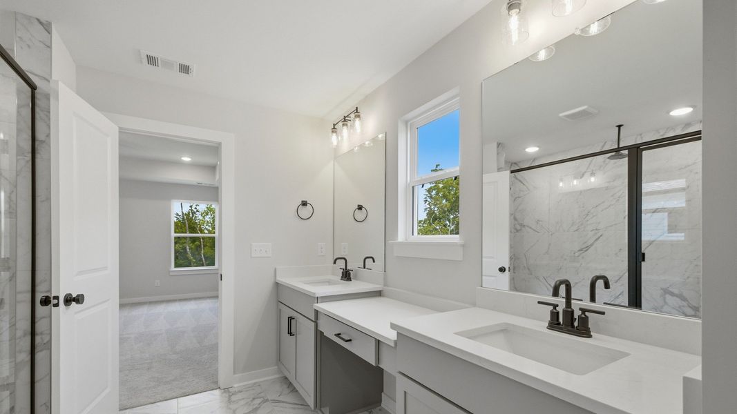 En-suite primary bathroom with dual vanity, tile flooring, and natural light En-suite primary bathroom with dual vanity, tile flooring, and natural light