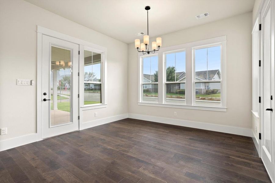 Unfurnished dining area featuring dark hardwood / wood-style flooring, a healthy amount of sunlight, and a notable chandelier