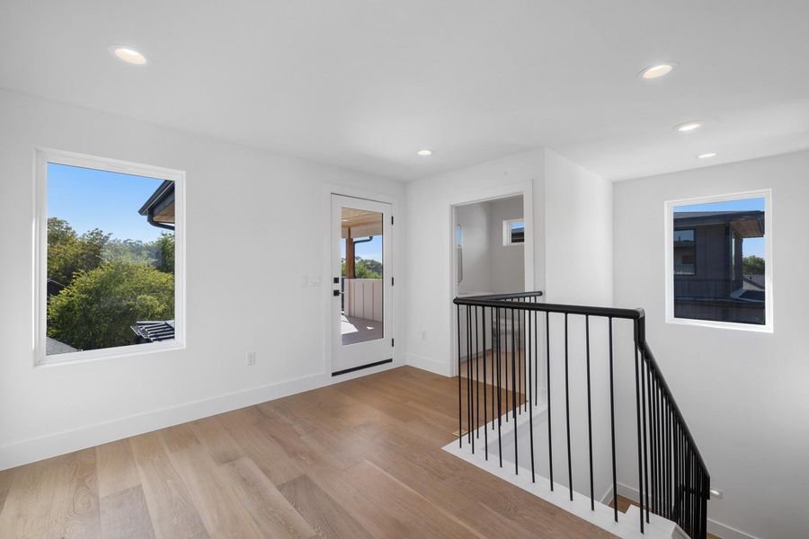 Hallway featuring recessed lighting, light wood-type flooring, and an upstairs landing Hallway featuring recessed lighting, light wood-type flooring, and an upstairs landing