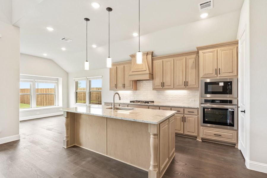 Kitchen with large center island, light wood cabinets, granite countertops, and stainless steel double oven Kitchen with large center island, light wood cabinets, granite countertops, and stainless steel double oven