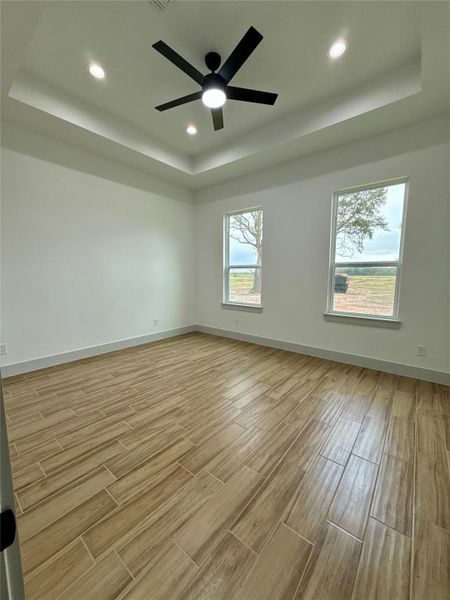 This room features a modern ceiling fan, recessed lighting, and wood-look tile flooring. It has two large windows that provide natural light and a view of the outdoors, with a simple, clean design. This room features a modern ceiling fan, recessed lighting, and wood-look tile flooring. It has two large windows that provide natural light and a view of the outdoors, with a simple, clean design.