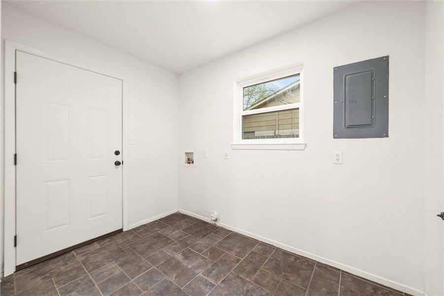 Laundry area featuring washer hookup, stone finish floor, laundry area, electric panel, and baseboards Laundry area featuring washer hookup, stone finish floor, laundry area, electric panel, and baseboards