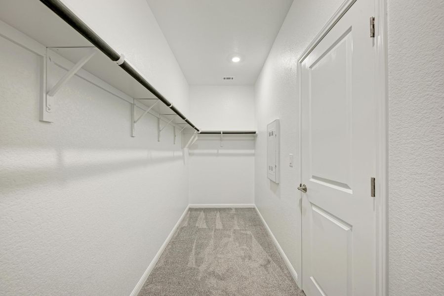 A well-lit, neutral-toned closet offers ample storage with practical shelving and hanging rods.