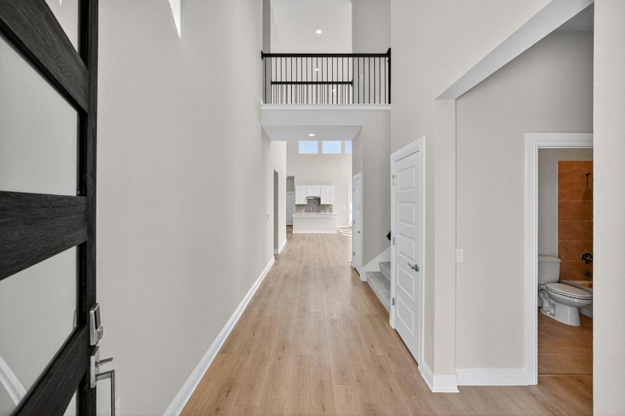 Hall featuring light wood-type flooring and a high ceiling Hall featuring light wood-type flooring and a high ceiling