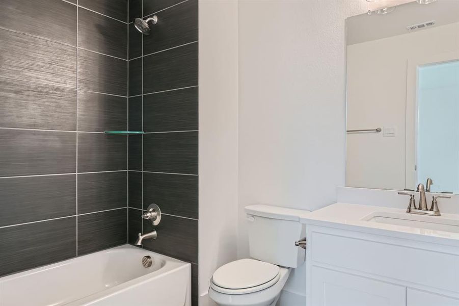 Full bathroom featuring vanity, toilet, and tiled shower / bath combo