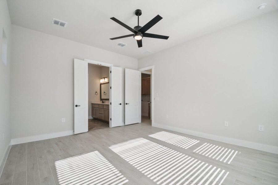 Unfurnished bedroom featuring light wood-type flooring, ceiling fan, and ensuite bath