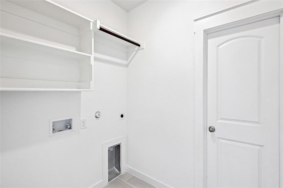 Laundry area with electric dryer hookup, hookup for a washing machine, light tile patterned flooring, and gas dryer hookup