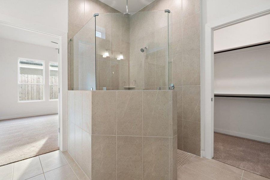 Full bath with carpet flooring, a walk in shower, tile patterned flooring, and a walk in closet