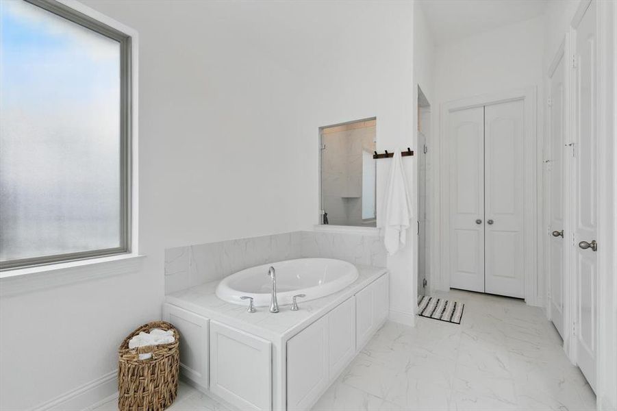 Full bathroom with a bath, a marble finish shower, light marble finish floors, and a closet
