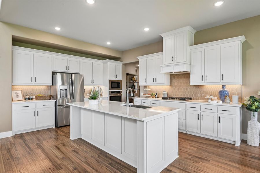 Kitchen with white cabinets, large center island with sink, stainless steel appliances, and hardwood floors Kitchen with white cabinets, large center island with sink, stainless steel appliances, and hardwood floors