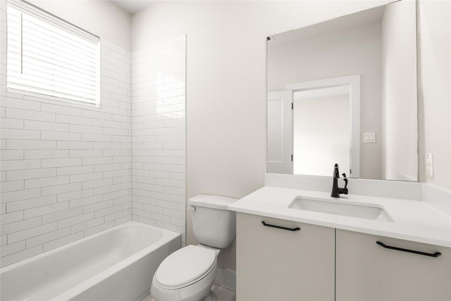 The secondary full bath keeps things clean and timeless with quartz counters, an undermount sink, matte black fixtures, and a tiled tub/shower surround.