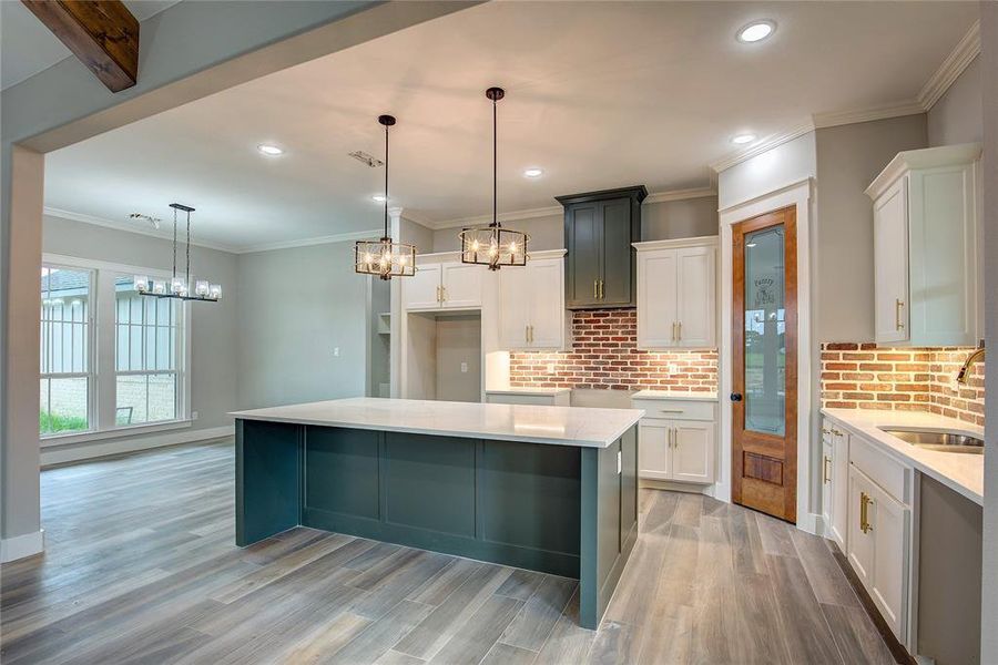 Kitchen featuring light hardwood / wood-style floors, sink, a center island, and white cabinets Kitchen featuring light hardwood / wood-style floors, sink, a center island, and white cabinets