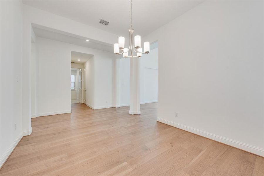 Unfurnished dining area featuring light hardwood / wood-style floors and an inviting chandelier