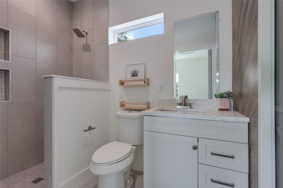 En Suite bathroom for bedroom number two features a walk-in shower, custom wood accent wall, sliding barn door entry and a Quartz countertop. The closet doors are to the right of the vanity cabinet. En Suite bathroom for bedroom number two features a walk-in shower, custom wood accent wall, sliding barn door entry and a Quartz countertop. The closet doors are to the right of the vanity cabinet.