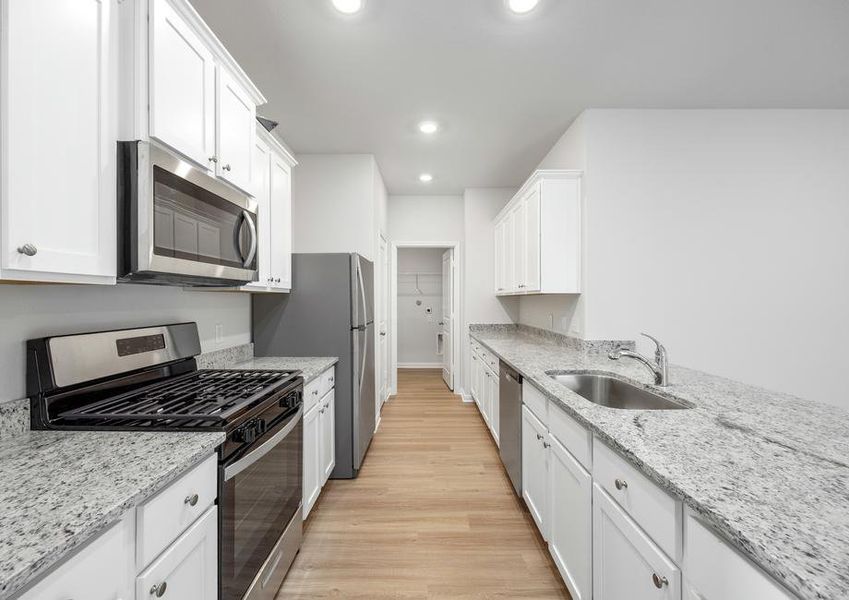 The kitchen has stainless steel appliances and plank flooring.