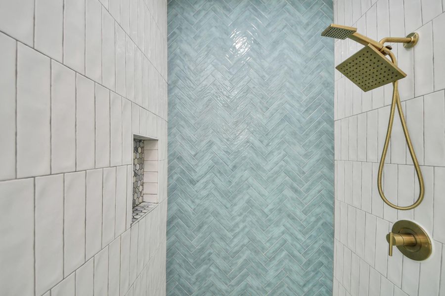 Walk-in shower featuring a herringbone-patterned blue tile accent wall, sleek brass fixtures, and a convenient built-in shelf. Walk-in shower featuring a herringbone-patterned blue tile accent wall, sleek brass fixtures, and a convenient built-in shelf.
