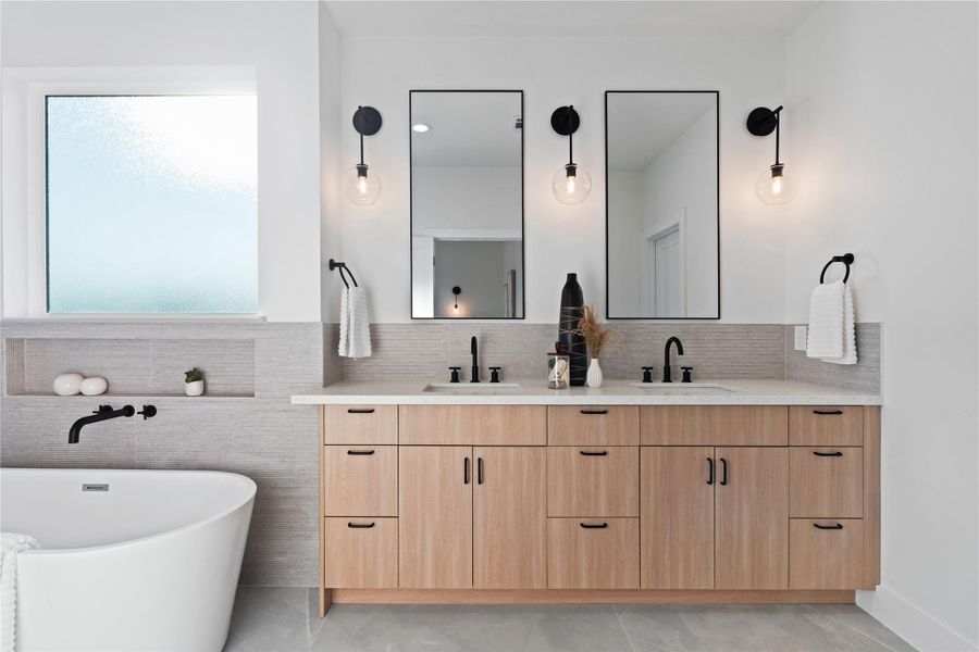 The primary ensuite features a dual vanity set against a stunning neutral gray fluted tile that extends behind the sinks and wraps seamlessly into the shower. This cohesive design blends modern elegance with a serene, spa-like feel.