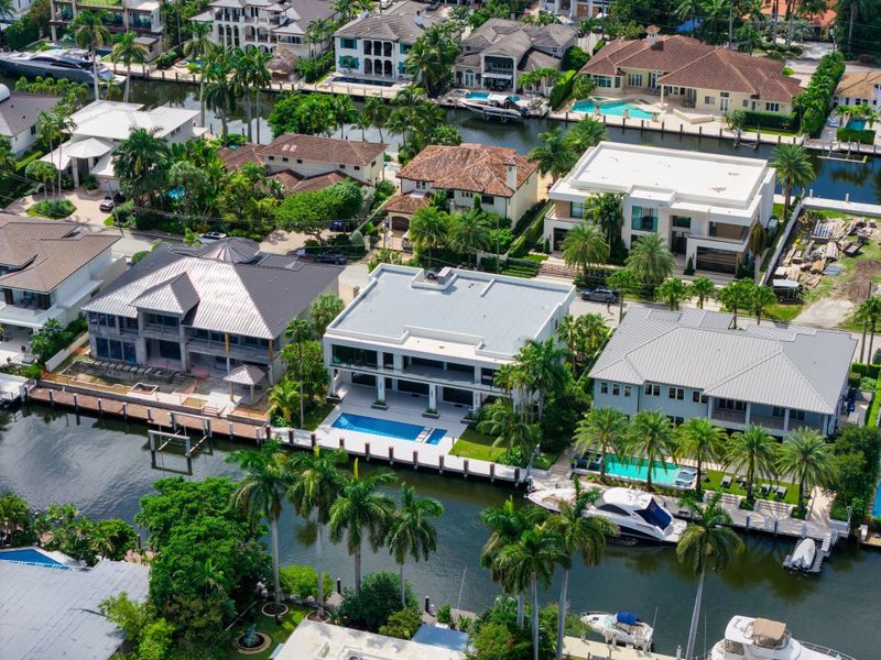 A direct overhead shot of a modern white residence with sleek architecture, set along the canal with tropical landscaping. A direct overhead shot of a modern white residence with sleek architecture, set along the canal with tropical landscaping.