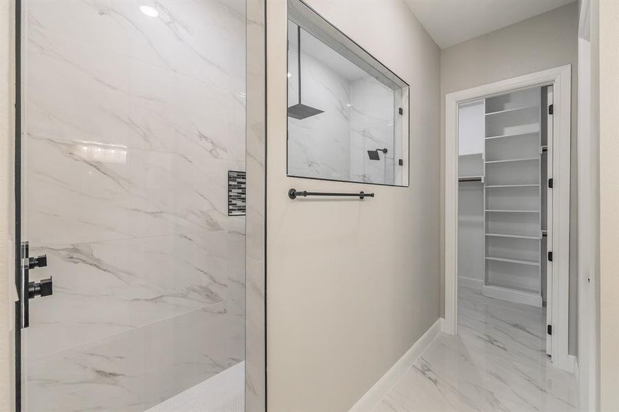 Full bathroom with marble finish floors, a marble finish shower, a spacious closet, and baseboards Full bathroom with marble finish floors, a marble finish shower, a spacious closet, and baseboards