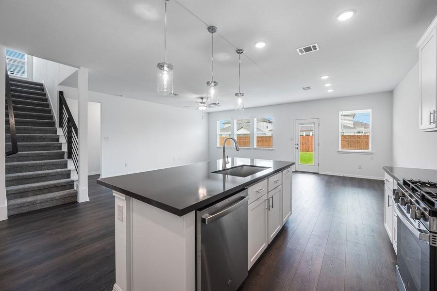 Kitchen featuring a sink, stainless steel appliances, dark countertops, dark wood-style floors, and open floor plan