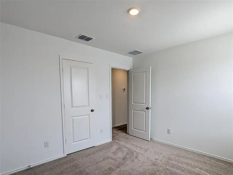 An inviting room features plush carpeting and recessed lighting, ready for personalization.