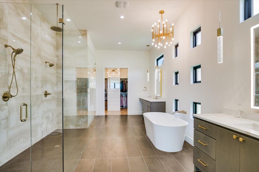 A spacious primary bath offering a grand walk-in shower and a free-standing tub, perfectly illuminated by unique high windows.