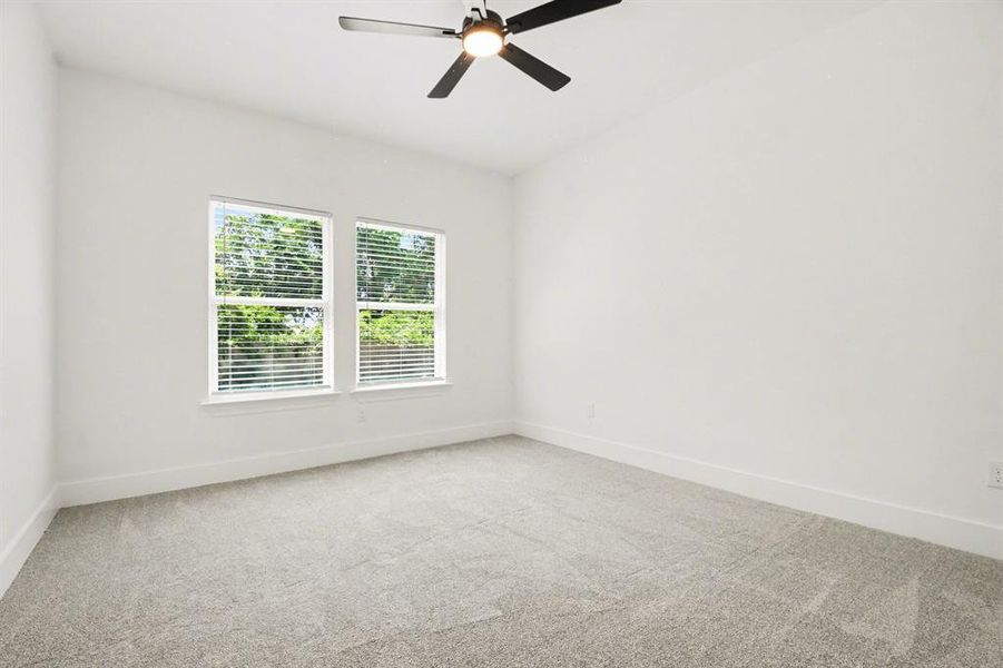 Bright room featuring two windows with blinds, a ceiling fan with integrated lighting, and carpeted flooring