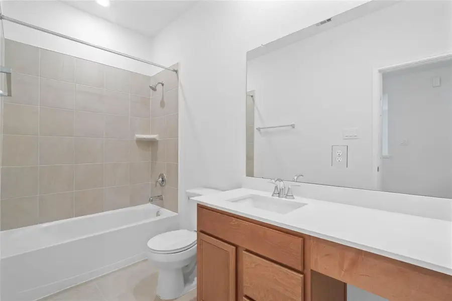 The secondary bathroom showcases tile flooring, a bath/shower combo with Daltile tile surround, vanity with knee space and a stunning light countertop, a stylish mirror, sleek fixtures, and contemporary finishes throughout. The secondary bathroom showcases tile flooring, a bath/shower combo with Daltile tile surround, vanity with knee space and a stunning light countertop, a stylish mirror, sleek fixtures, and contemporary finishes throughout.