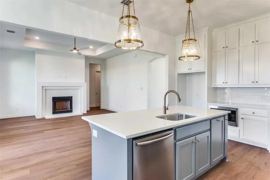 Kitchen with gray cabinetry, a center island with sink, a ceiling fan, appliances with stainless steel finishes, and pendant lighting Kitchen with gray cabinetry, a center island with sink, a ceiling fan, appliances with stainless steel finishes, and pendant lighting