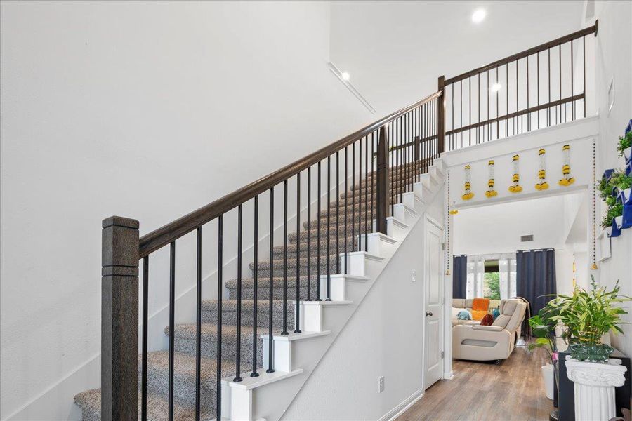 Stairway with a towering ceiling and wood finished floors