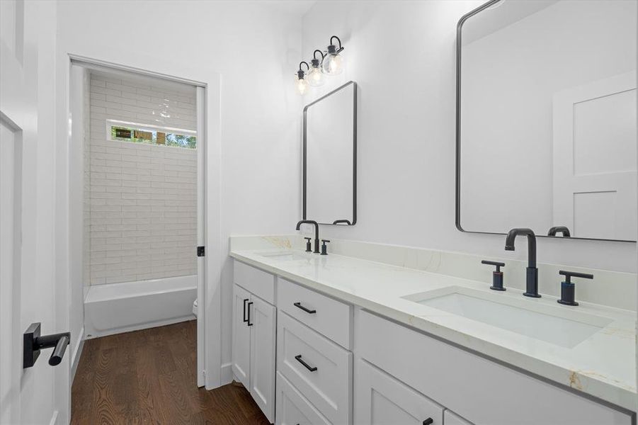 Full bathroom featuring dark wood-style flooring, double vanity, and shower combination Full bathroom featuring dark wood-style flooring, double vanity, and shower combination