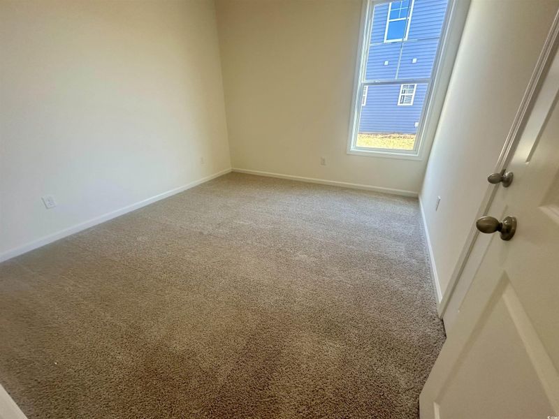 Spare room featuring light carpet and baseboards